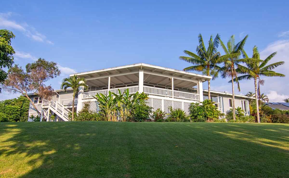 Hawaii Island Recovery residence with covered lanai, palm trees and lawn in Kailua-Kona