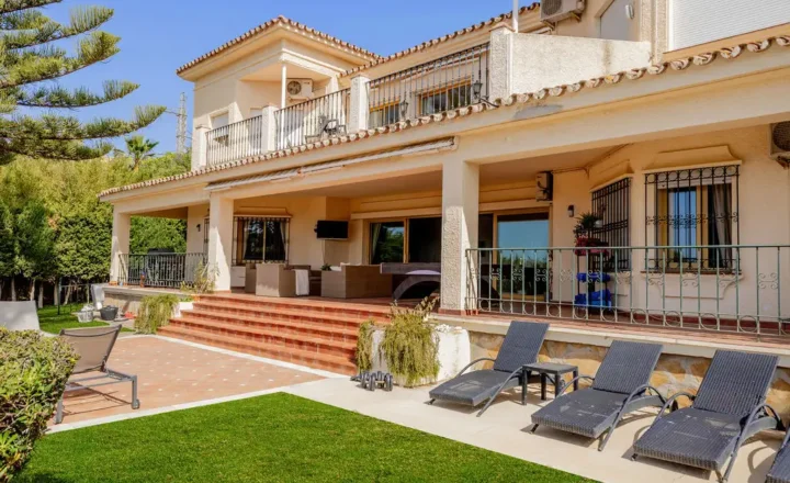 Exterior of InHarmoni's residential villa with covered terrace and garden loungers