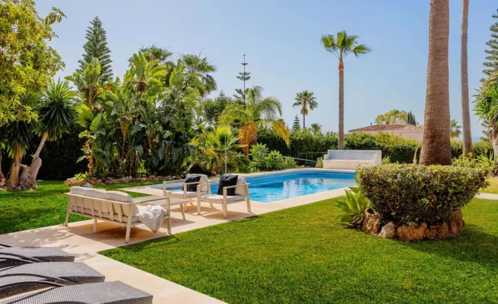 Swimming pool surrounded by palms and garden seating at InHarmoni Rehab in El Paraiso