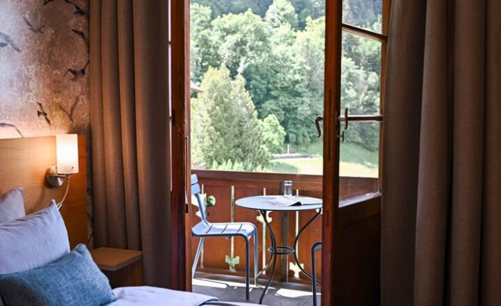 Bedroom with a bed and open balcony doors at NEOVIVA's hotel accommodation in Vitznau