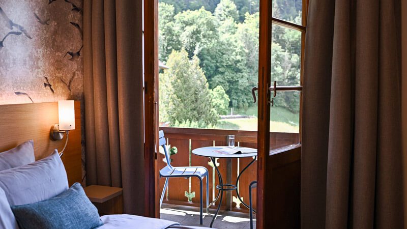 Bedroom with a bed and open balcony doors at NEOVIVA's hotel accommodation in Vitznau