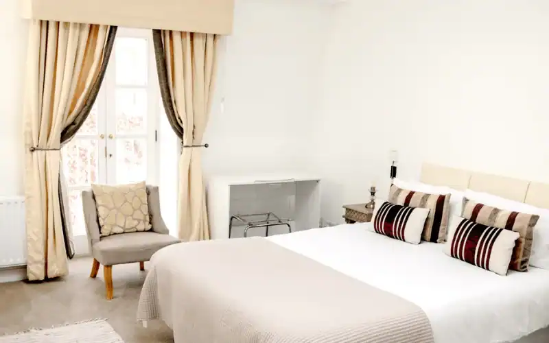 Private bedroom with a double bed, bedside tables and armchair at PROMIS Kendrick Mews