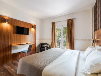 Private bedroom with desk, television and balcony doors at Satori Recovery in Manilva
