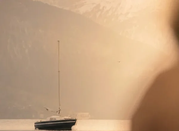 Sailboat on a lake with mountains beyond, pictured by The Kusnacht Practice