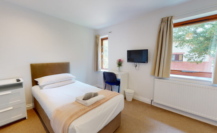 Single bedroom with desk, television and large windows at Banbury Lodge