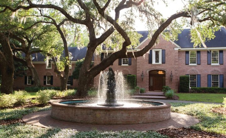 Fountain and estate building beneath oak trees at The Guest House